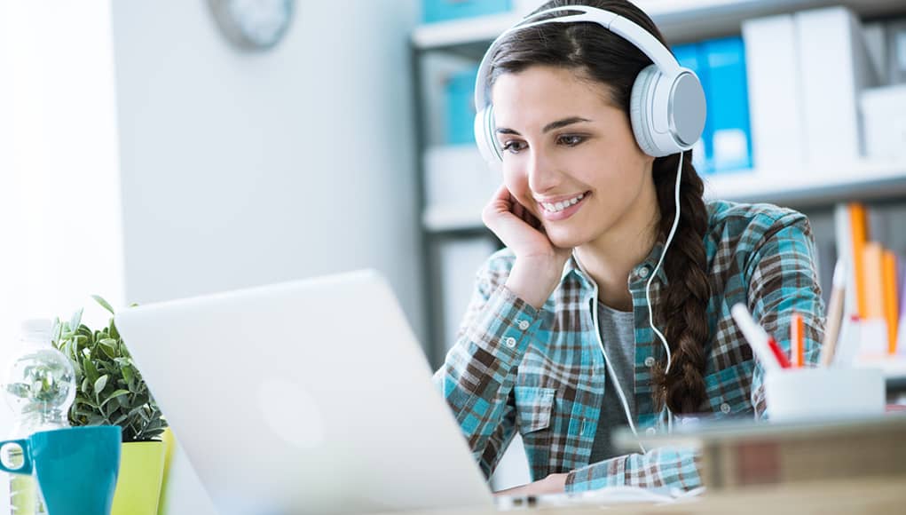 girl with headphones using laptop listening to podcast feature image